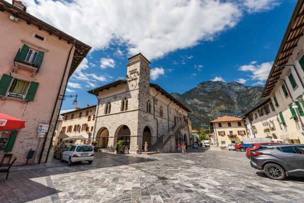 Ein Platz in Riva del Garda mit dem Rathaus und Bergen im Hintergrund.