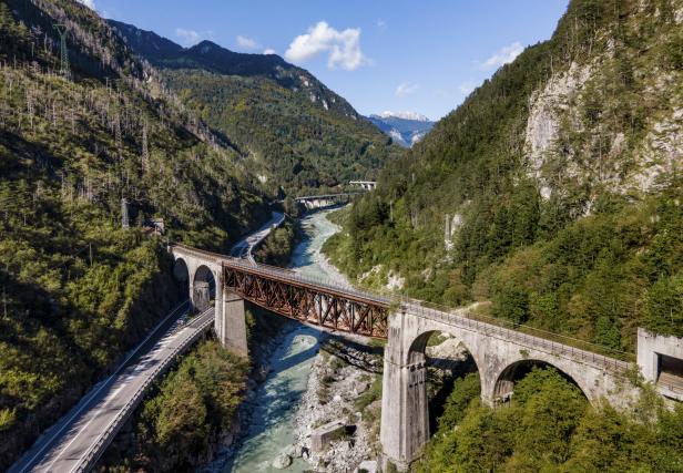 Eine malerische Landschaft mit einer Brücke über einen Fluss in den Bergen.