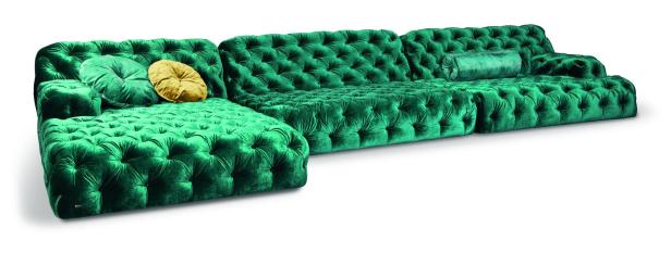 Ein smaragdgrünes, getuftetes Ecksofa mit Samtbezug und Zierkissen.