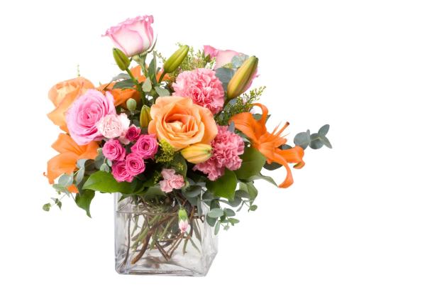 Ein Blumenstrauß mit Rosen, Nelken und Lilien in einer Glasvase.