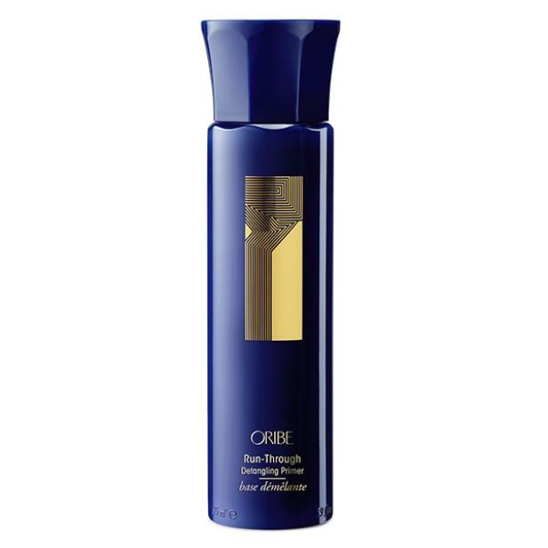 Eine Flasche Oribe „Run-Through Detangling Primer“ in Dunkelblau mit goldenen Akzenten.