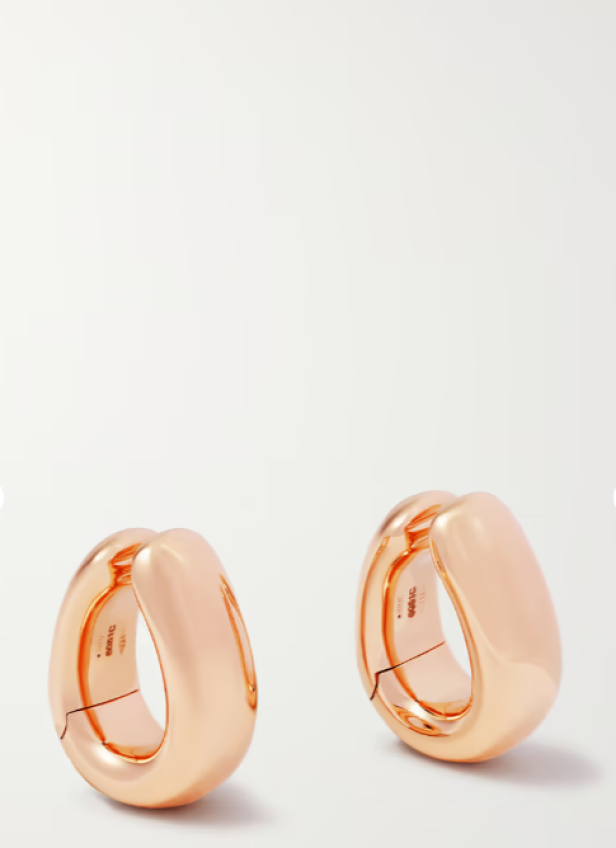 Nahaufnahme von zwei goldenen Ohrringen vor einem weißen Hintergrund.