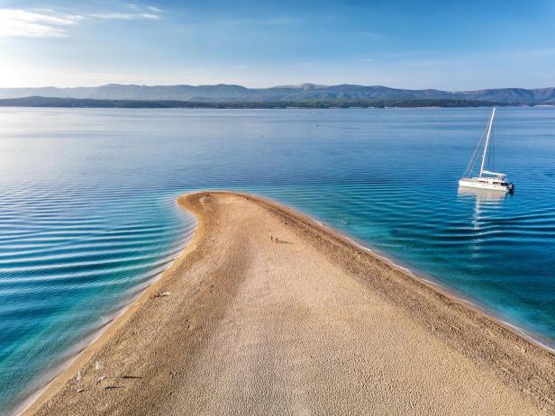 Luftaufnahme von Zlatni Rat, einer Landzunge mit einem Segelboot im Meer.