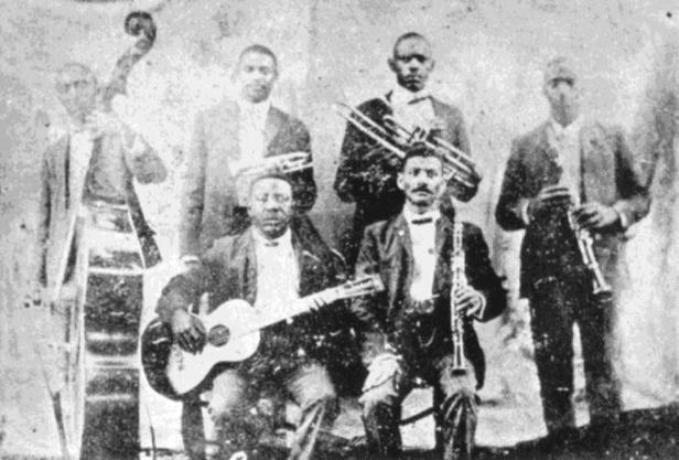 Eine Gruppe von sechs afroamerikanischen Musikern mit ihren Instrumenten, vermutlich eine Jazzband.