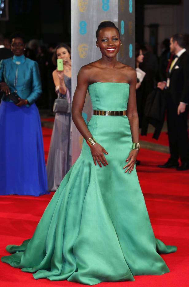 Lupita Nyong'o in einem grünen Kleid mit goldenem Gürtel auf dem roten Teppich.