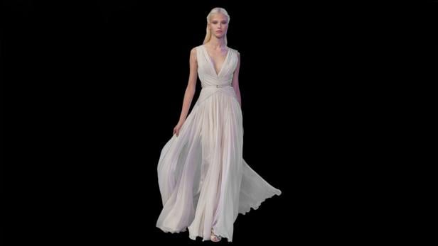 Eine Frau mit blonden Haaren trägt ein langes, weißes Kleid.