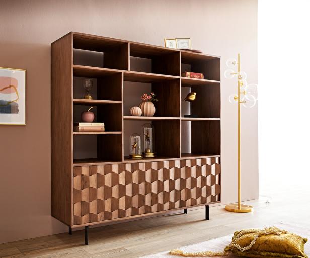 Ein Holzregal mit geometrischem Muster steht in einem Zimmer.