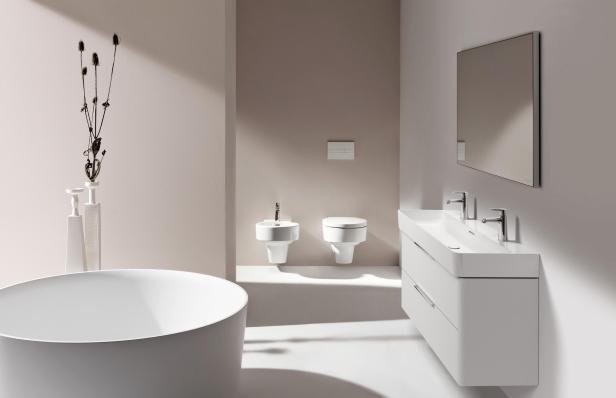 Ein modernes Badezimmer in Weiß und Beige mit Badewanne, Waschtisch und Toilette.