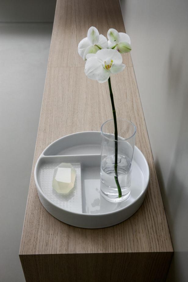 Eine weiße Orchidee in einem Glas Wasser auf einem Holztablett mit einem Stück Seife.