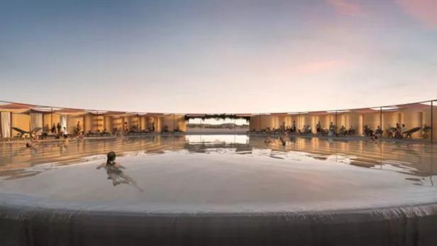 Ein großes, kreisförmiges Schwimmbecken mit Menschen an den Rändern bei Sonnenuntergang.