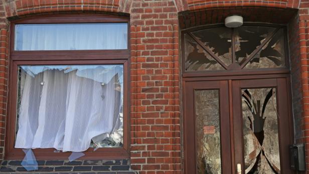 Ein Fenster und eine Tür eines Backsteingebäudes sind beschädigt.