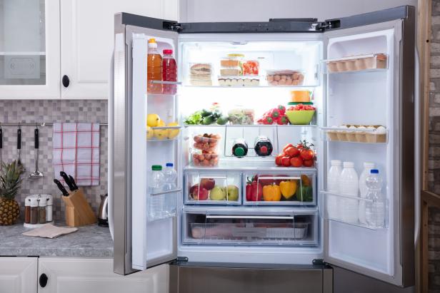 Ein geöffneter Kühlschrank gefüllt mit Lebensmitteln wie Obst, Gemüse und Getränken.