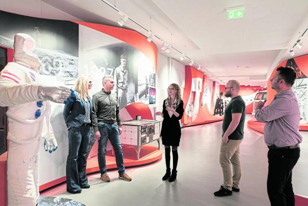 Eine Gruppe von Personen in einem Museum mit einer Ausstellung zum Thema Raumfahrt.