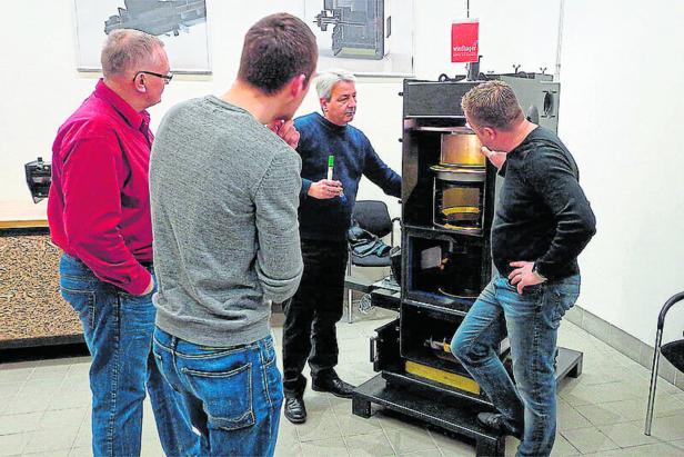 Vier Männer betrachten einen Ofen mit mehreren Fächern.