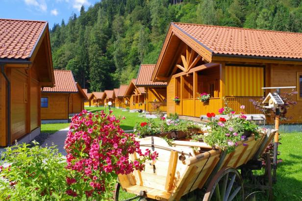 Das Feriendorf Oberreit mit Holzhäusern und blühenden Blumen im Vordergrund.