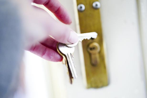 Hand mit Schlüssel beim Aufsperren einer Wohnungstüre.