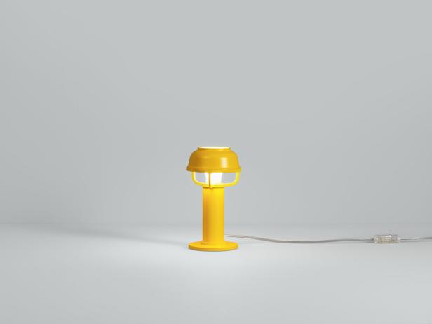 Eine gelbe Nachttischlampe leuchtet auf einem Tisch.