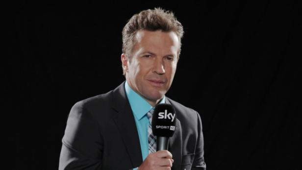 Ein Mann im Anzug hält ein Mikrofon von Sky Sport HD.
