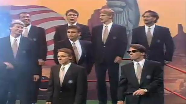 Das US-amerikanische Herren-Basketballteam bei den Olympischen Spielen 1992 in Anzügen vor einer US-Flagge.