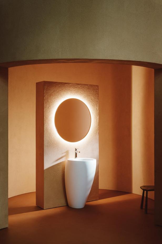 Ein freistehendes Waschbecken mit rundem Spiegel in einem Badezimmer mit Terrakotta-Farben.