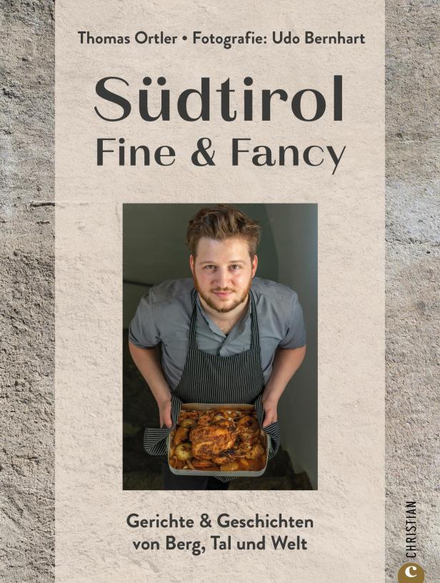 Ein Koch präsentiert ein Gericht auf dem Cover des Buches „Südtirol Fine & Fancy“.