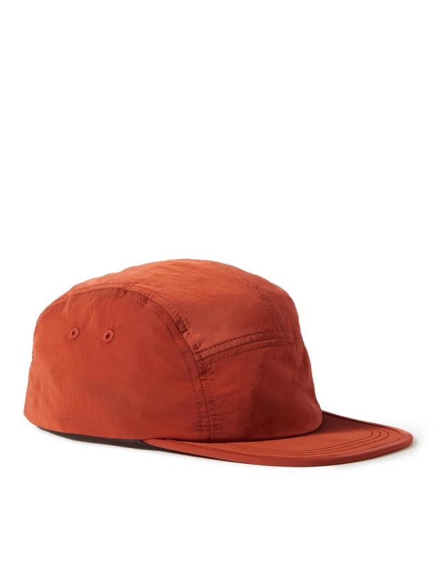 Eine orangefarbene Kappe mit flachem Schirm liegt auf einem weißen Hintergrund.
