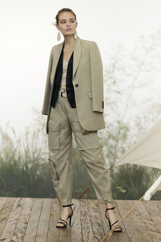 Eine Frau in einem beigen Hosenanzug mit Cargohose und schwarzen Sandalen.