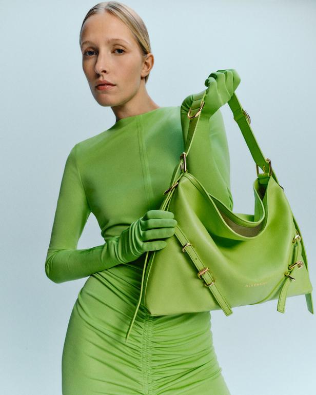 Eine Frau in einem grünen Kleid und Handschuhen hält eine grüne Givenchy-Handtasche.