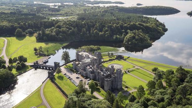 Luftaufnahme von Ashford Castle in Irland, umgeben von Seen und Wäldern.
