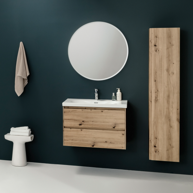 Ein Badezimmer mit einem Waschtisch aus Holz, einem runden Spiegel und einem hohen Schrank.