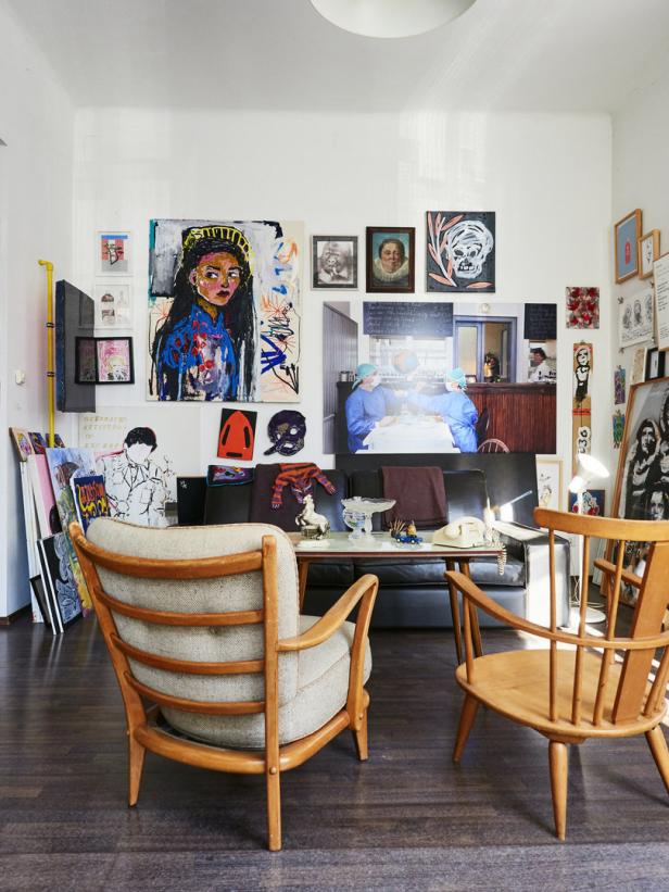 Ein Wohnzimmer mit Kunstwerken an der Wand und zwei Sesseln im Vordergrund.