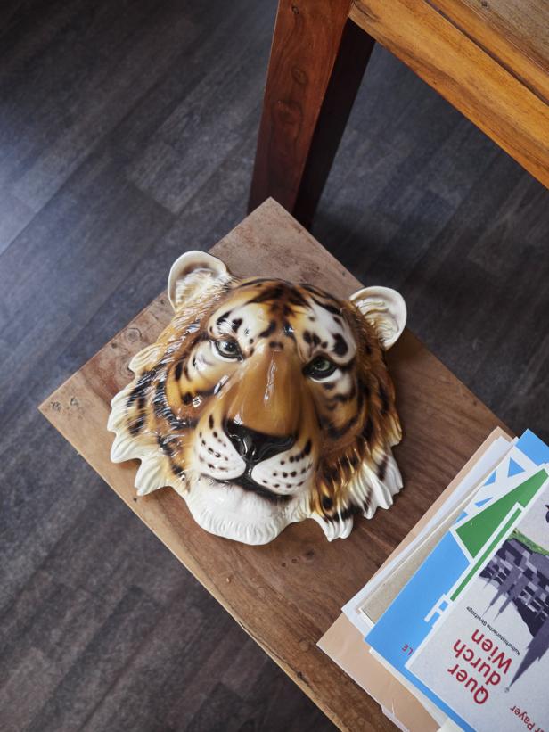 Eine Keramikmaske eines Tigers liegt auf einem kleinen Holztisch.