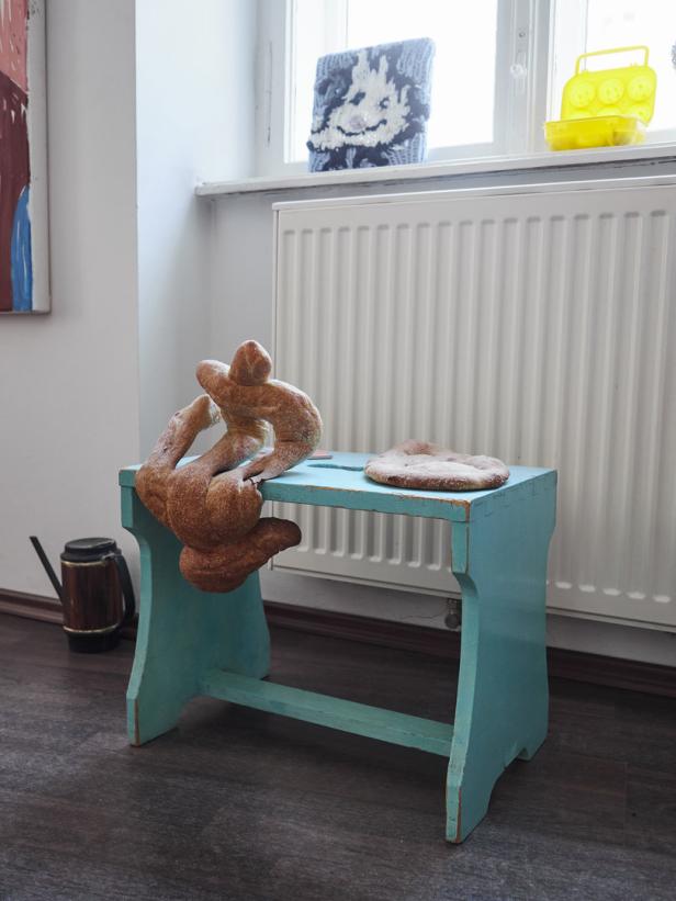 Eine blaue Holzbank mit Brotfiguren und einem Fladenbrot darauf.