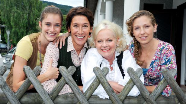Die humorige Krimiserie 'Vier Frauen und ein Todesfall' wird weiterproduziert. Vier Frauen lächeln hinter einem Holzzaun in die Kamera.