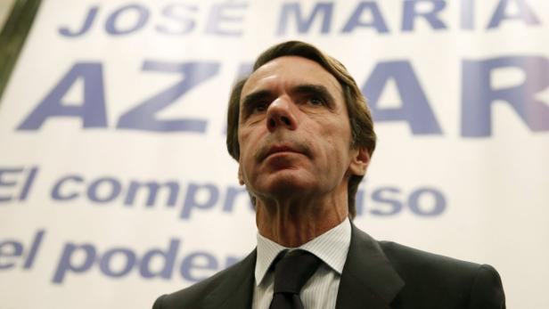 José María Aznar blickt vor einem Wahlplakat nach oben.