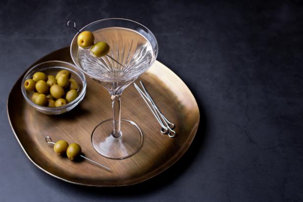 Ein Martini mit Oliven auf einem goldenen Tablett.