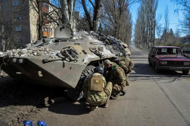 Ukrainian service members repair an Armoured Personnel Carrier in the front line city of Chasiv Yar