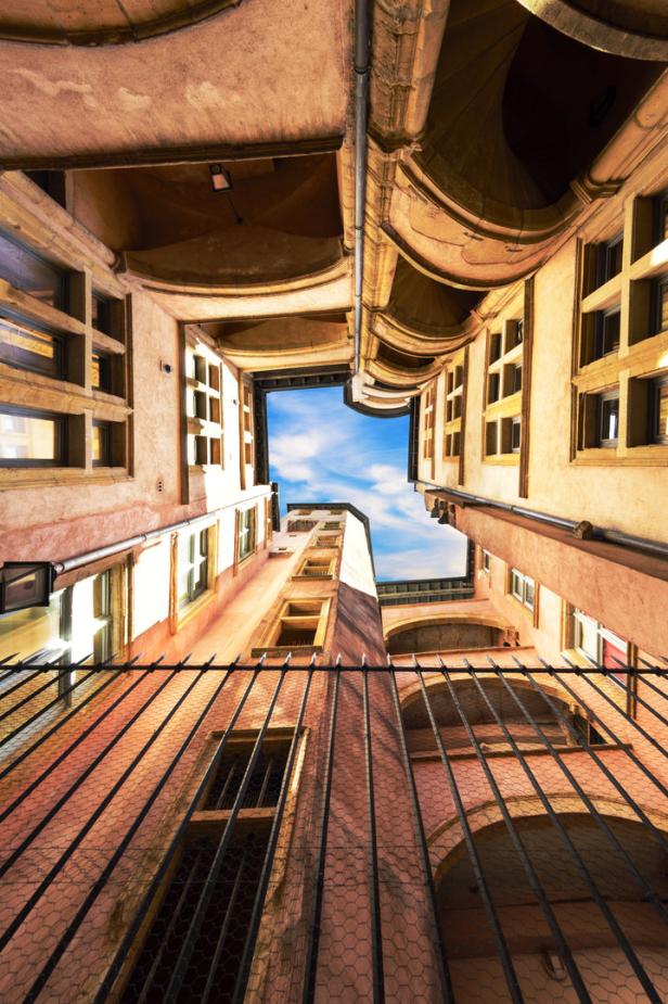 Blick von unten auf einen Innenhof mit rosa Gebäuden und blauem Himmel.