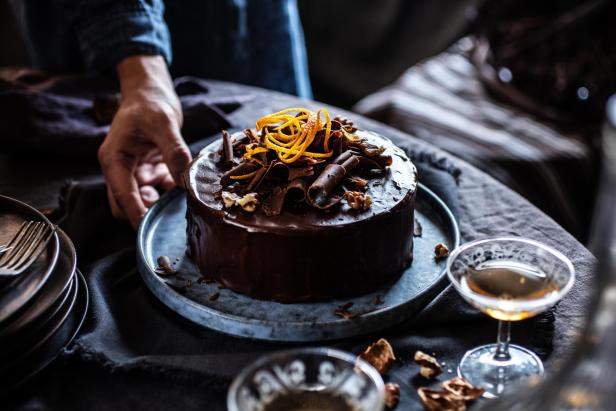 Ein Schokoladenkuchen ist mit Orangenschalen und Schokoladenraspeln dekoriert.