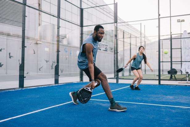 Ein Mann und eine Frau spielen Padel-Tennis auf einem blauen Platz.
