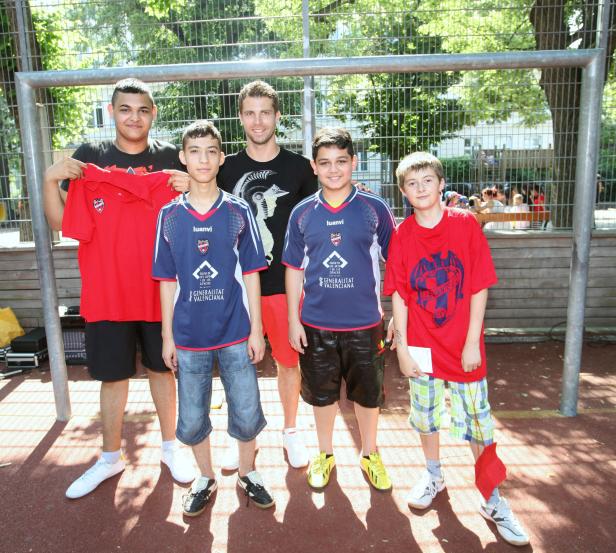 Eine Gruppe von Jungen und ein Mann posieren vor einem Fußballtor.