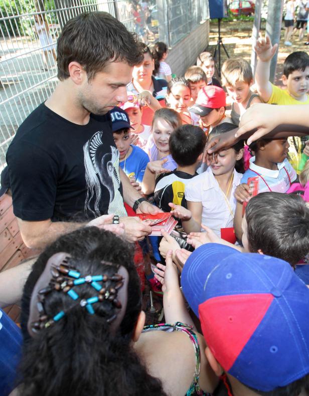Ein Mann gibt Autogramme an eine Gruppe von Kindern.