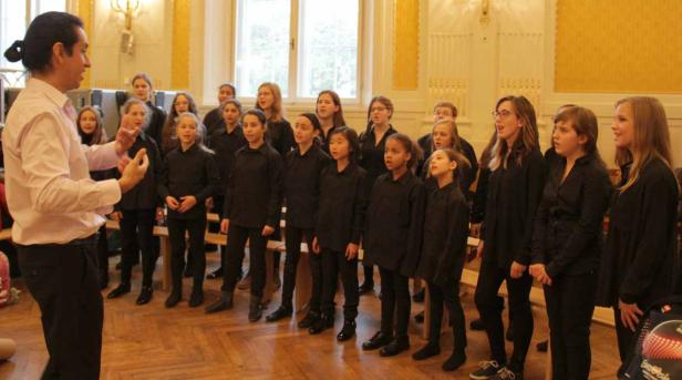 Ein Chor von Jugendlichen singt unter der Leitung eines Dirigenten.