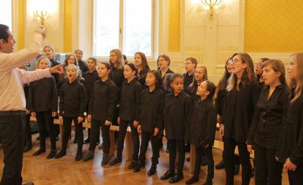 Ein Chor von Kindern und Jugendlichen singt unter der Leitung eines Dirigenten.