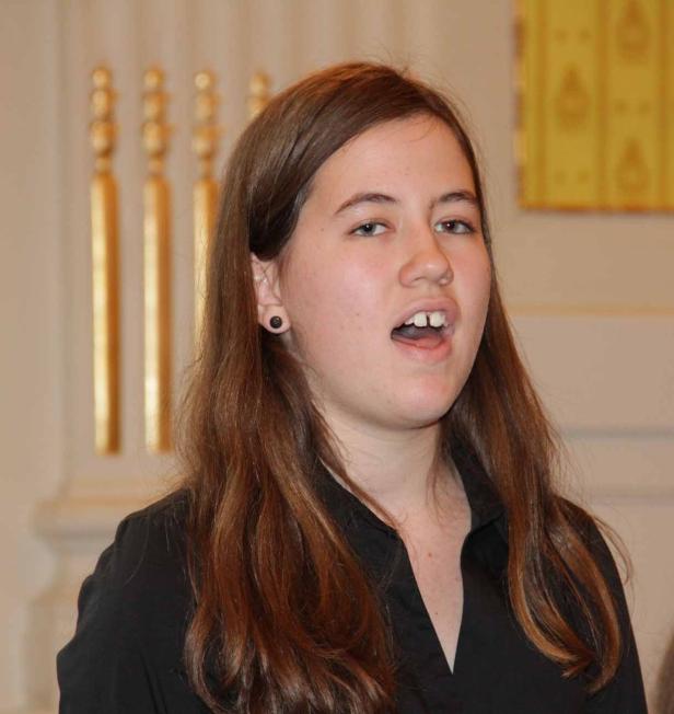 Eine junge Frau mit braunen Haaren singt.