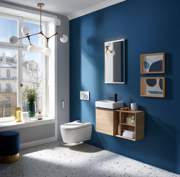 Ein modernes Badezimmer mit blauen Wänden, einem hängenden WC und einem Waschtisch mit Spiegel.
