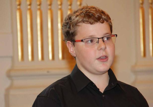 Ein junger Mann mit Brille und schwarzem Hemd schaut zur Seite.