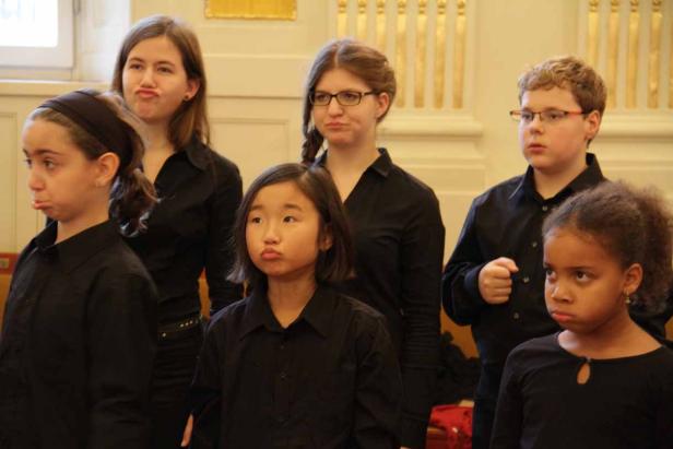 Eine Gruppe Kinder in schwarzen Hemden zieht missmutige Gesichter.