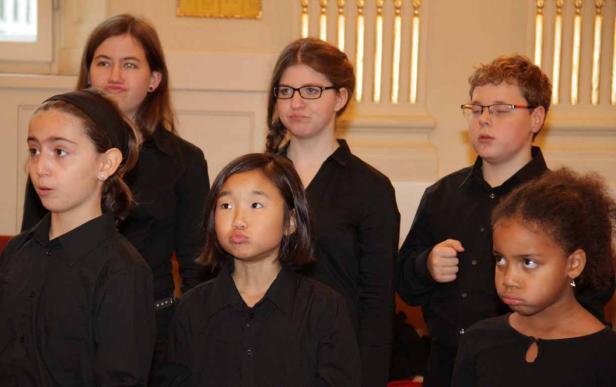 Eine Gruppe von Kindern in schwarzen Hemden steht zusammen.