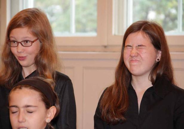 Drei junge Frauen in schwarzen Hemden, eine davon verzieht das Gesicht.